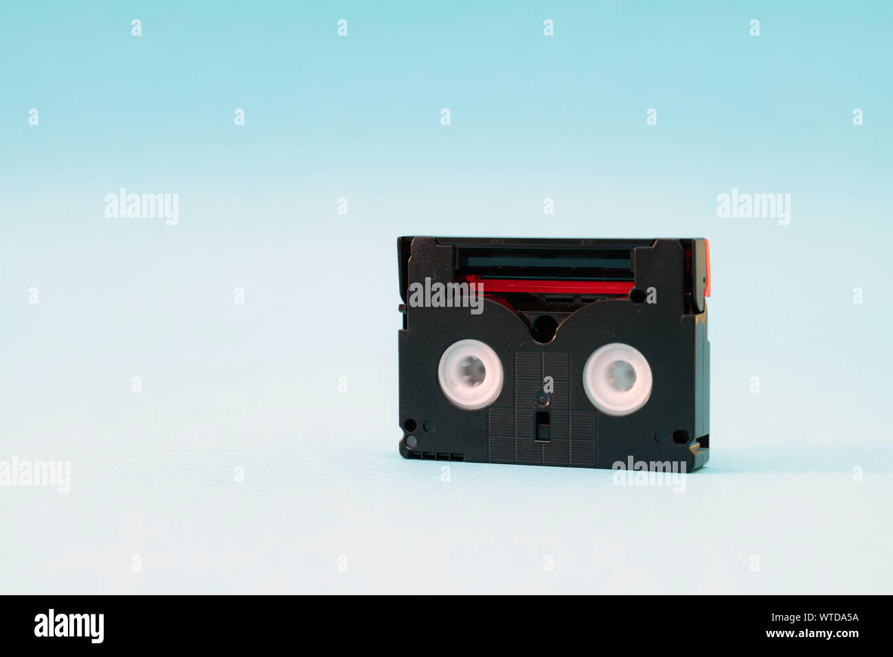 Vintage mini cassette DV utilisé pour l'enregistrement vidéo retour dans une journée. Plastique, ruban magnétique, film analogique sur fond bleu Banque D'Images
