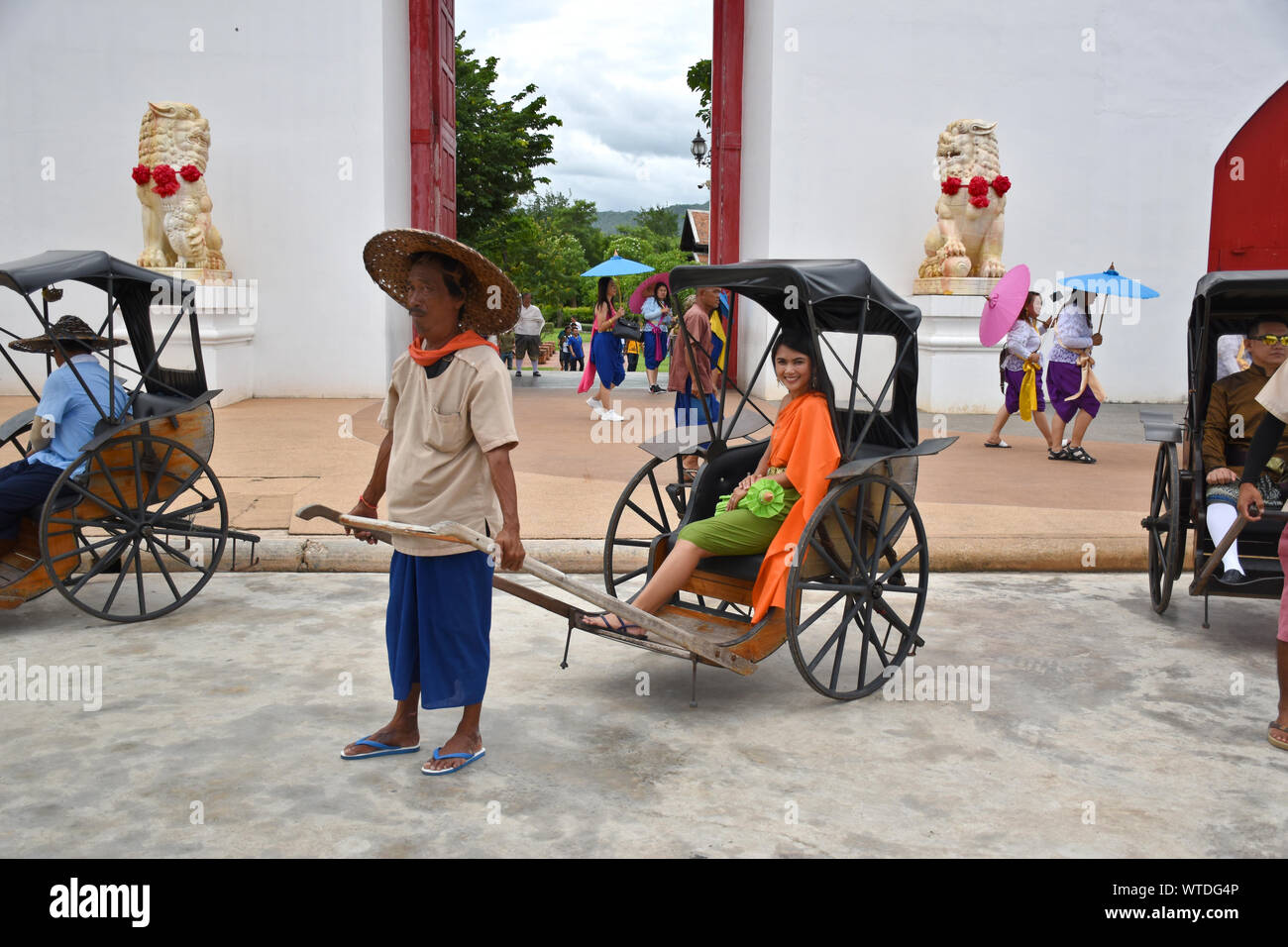 Kanchanaburi, Thaïlande, 09.09.2019 : belle fille thaïe traditionnelle thaïlandaise, en robe de siamois dans un vieux vélo-taxi en face de l'entrée de 'Mallika Cit Banque D'Images