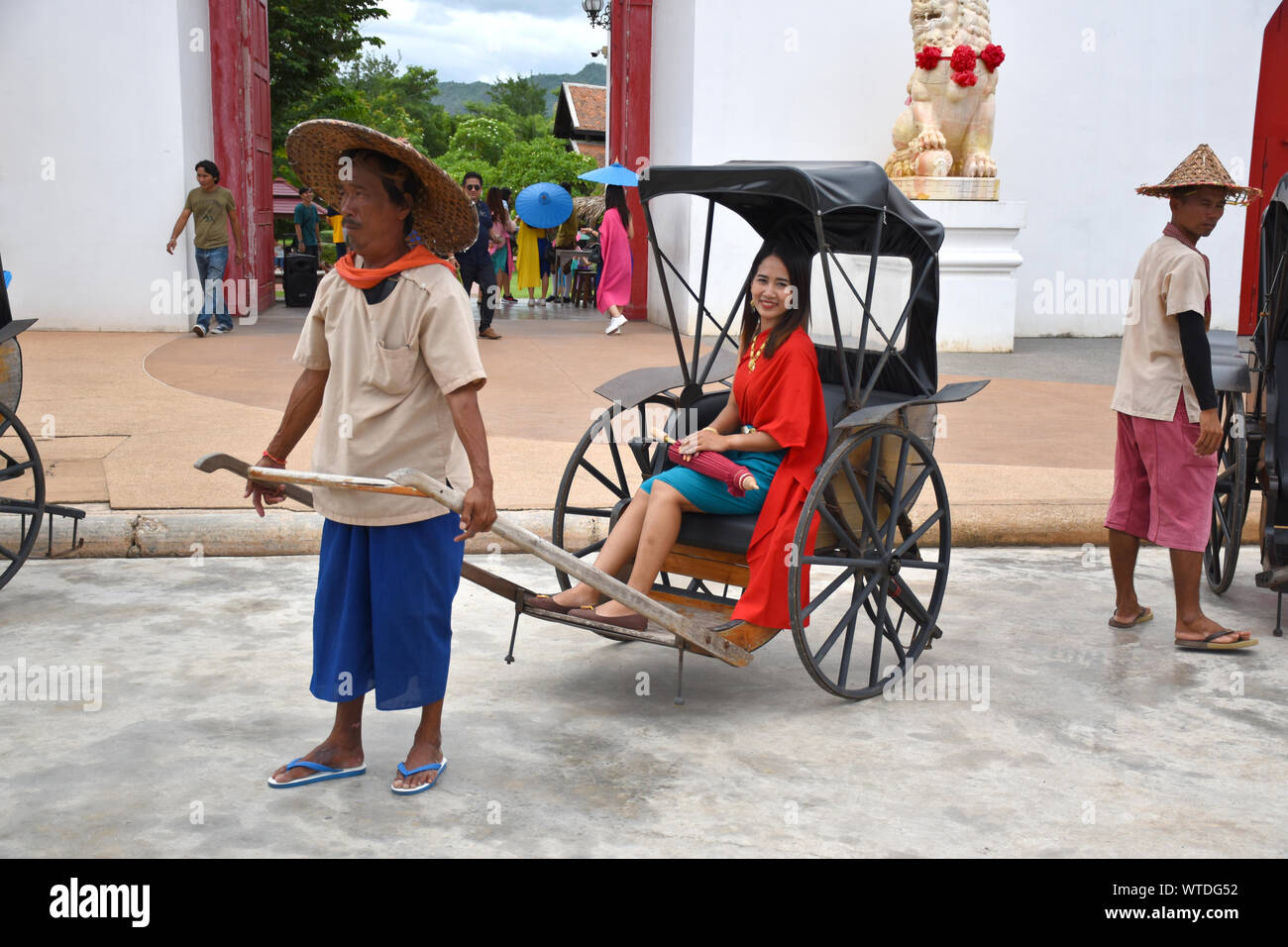 Kanchanaburi, Thaïlande, 09.09.2019 : belle fille thaïe traditionnelle thaïlandaise, en robe de siamois dans un vieux vélo-taxi en face de l'entrée de 'Mallika Cit Banque D'Images