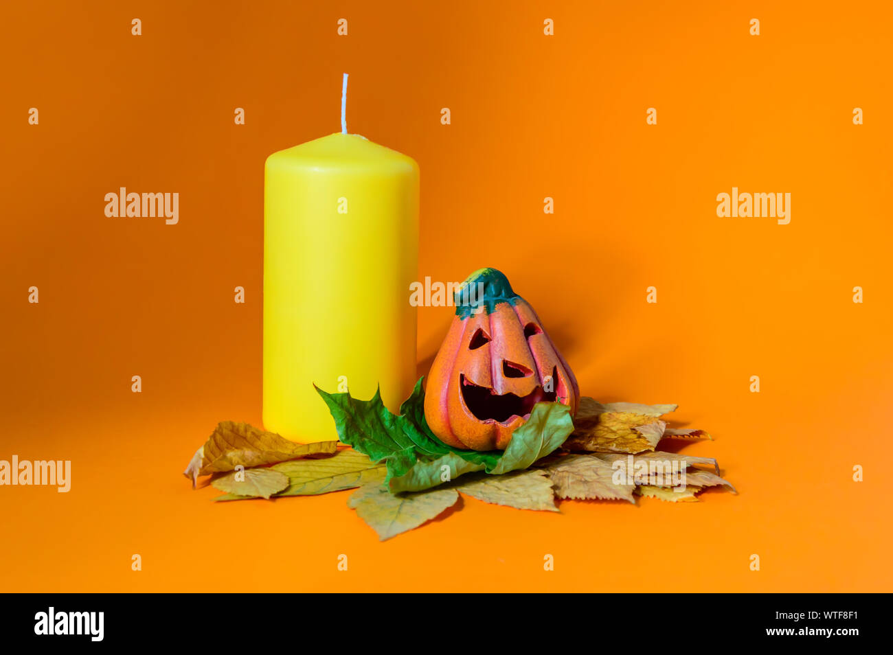 Composition avec céramique décorative Halloween citrouille jack-o-lanterne sur l'automne les feuilles sèches et bougie jaune Banque D'Images