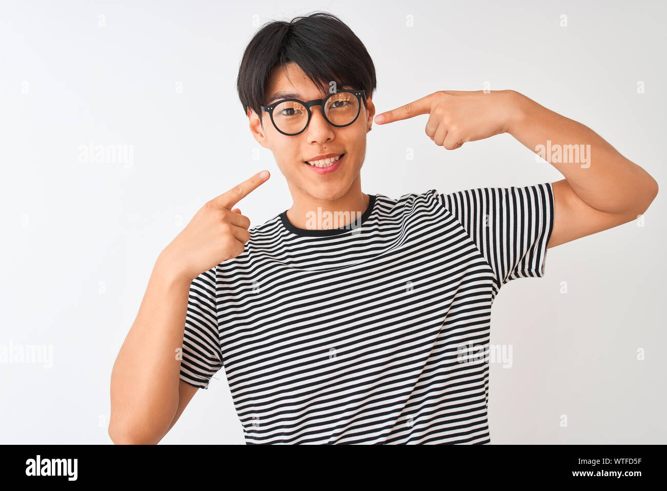 L'homme chinois portant des lunettes et de la marine t-shirt à rayures sur  fond blanc isolé permanent gai souriant et montrant les dents avec les  doigts pointant Photo Stock - Alamy