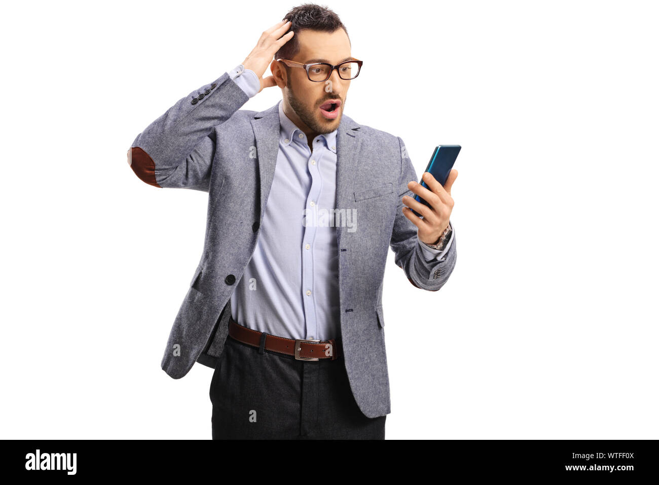 Choqué Jeune homme tenant la tête et en regardant un téléphone mobile isolé sur fond blanc Banque D'Images Choqué Jeune homme tenant la tête et en regardant un téléphone mobile isolé sur fond blanc Banque D'Images