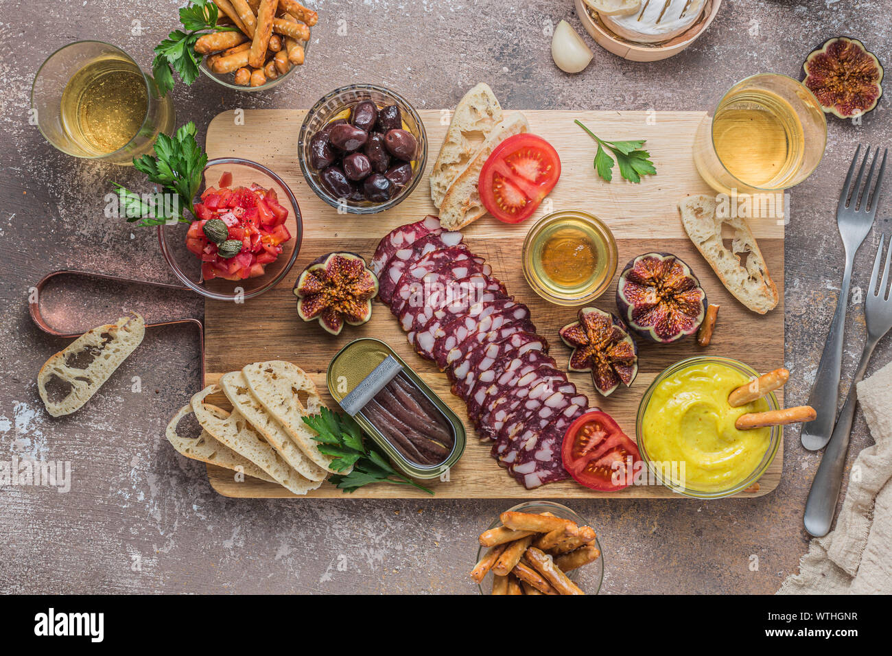 Salami, fromage, pain, anchoves et dip alioli sur planche de bois, mise à plat. Banque D'Images