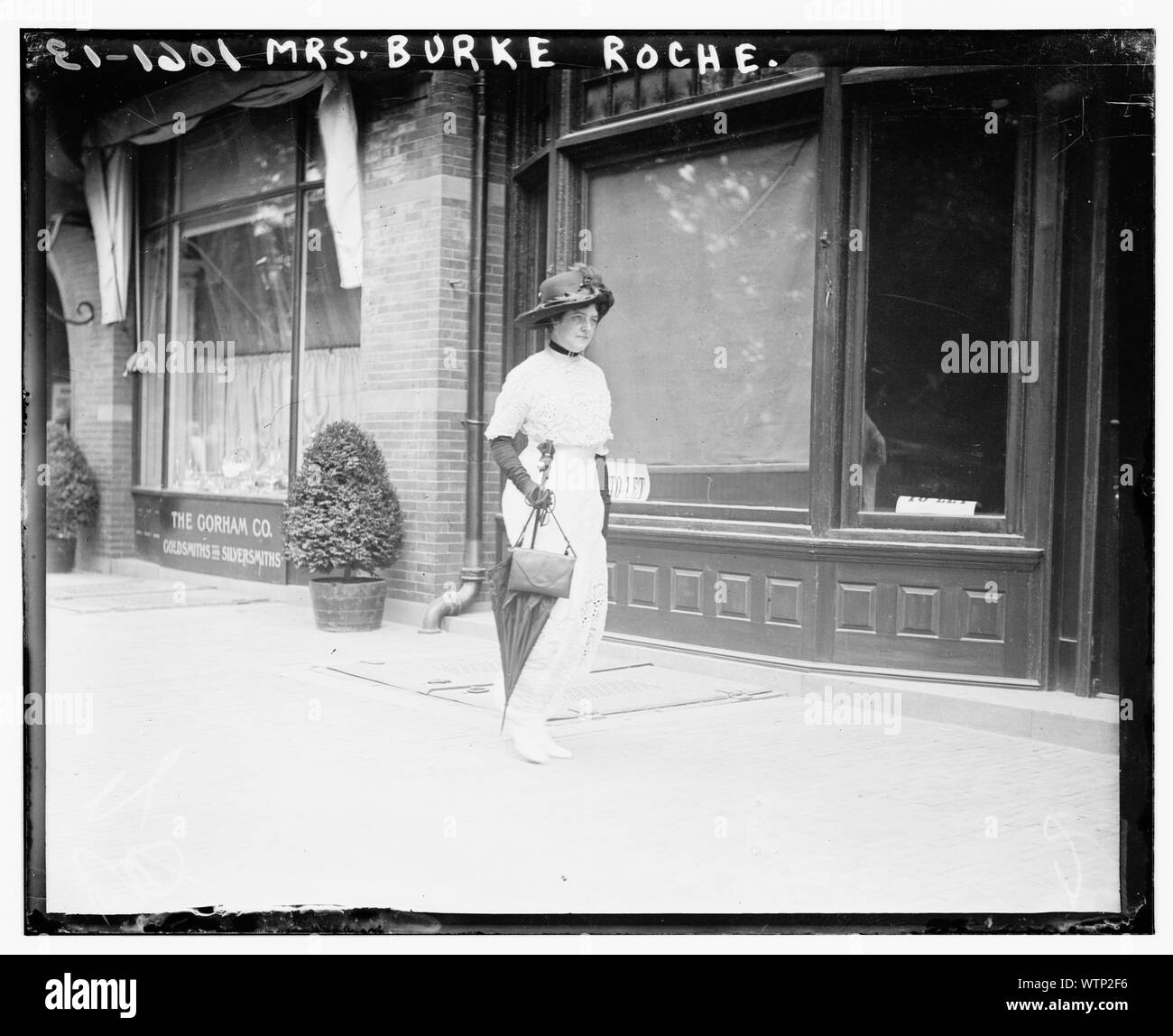 Mme Burke Roche marche sur trottoir avec parasol Banque D'Images