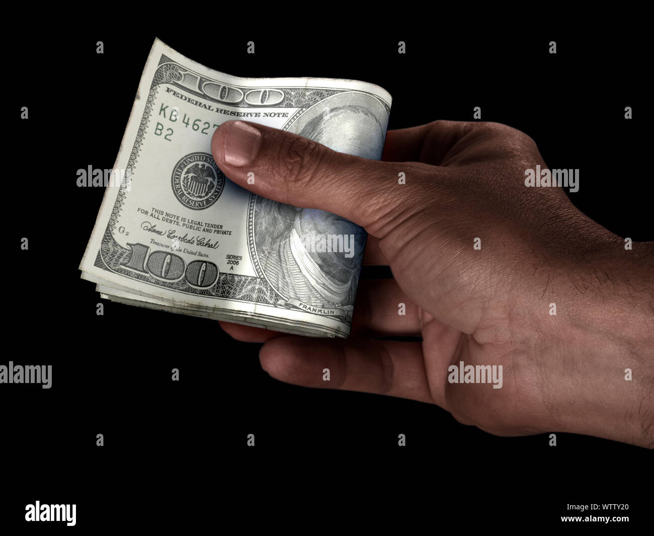 Un homme de race noire part remettre une liasse de billets de banque en dollars US plié sur un fond isolé Banque D'Images