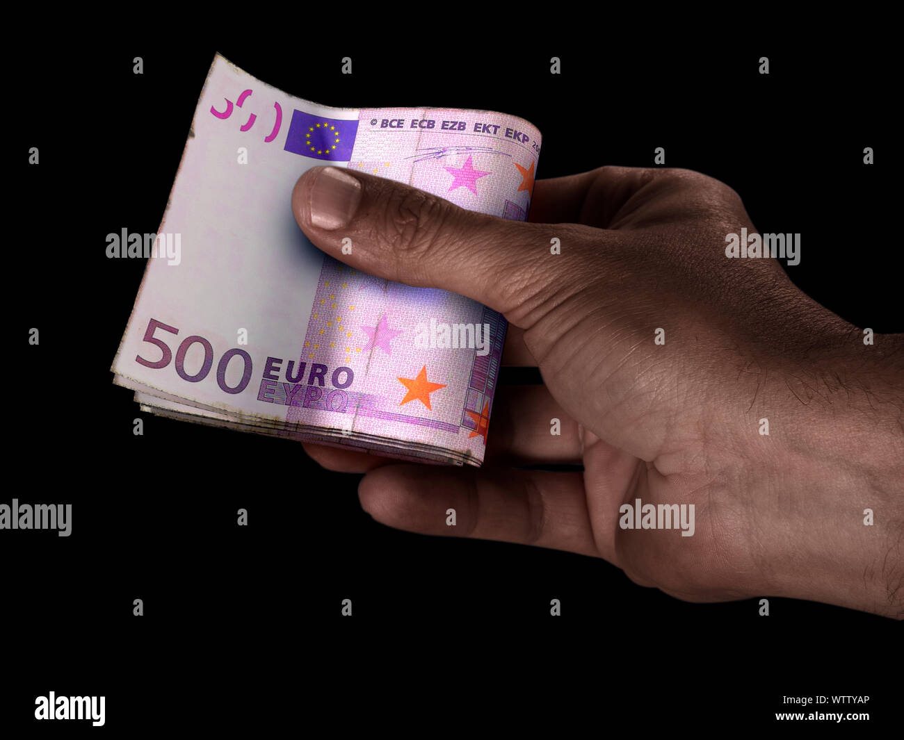 Un homme de race noire part remettre une liasse de billets de banque euro européenne pliée sur un fond isolé Banque D'Images