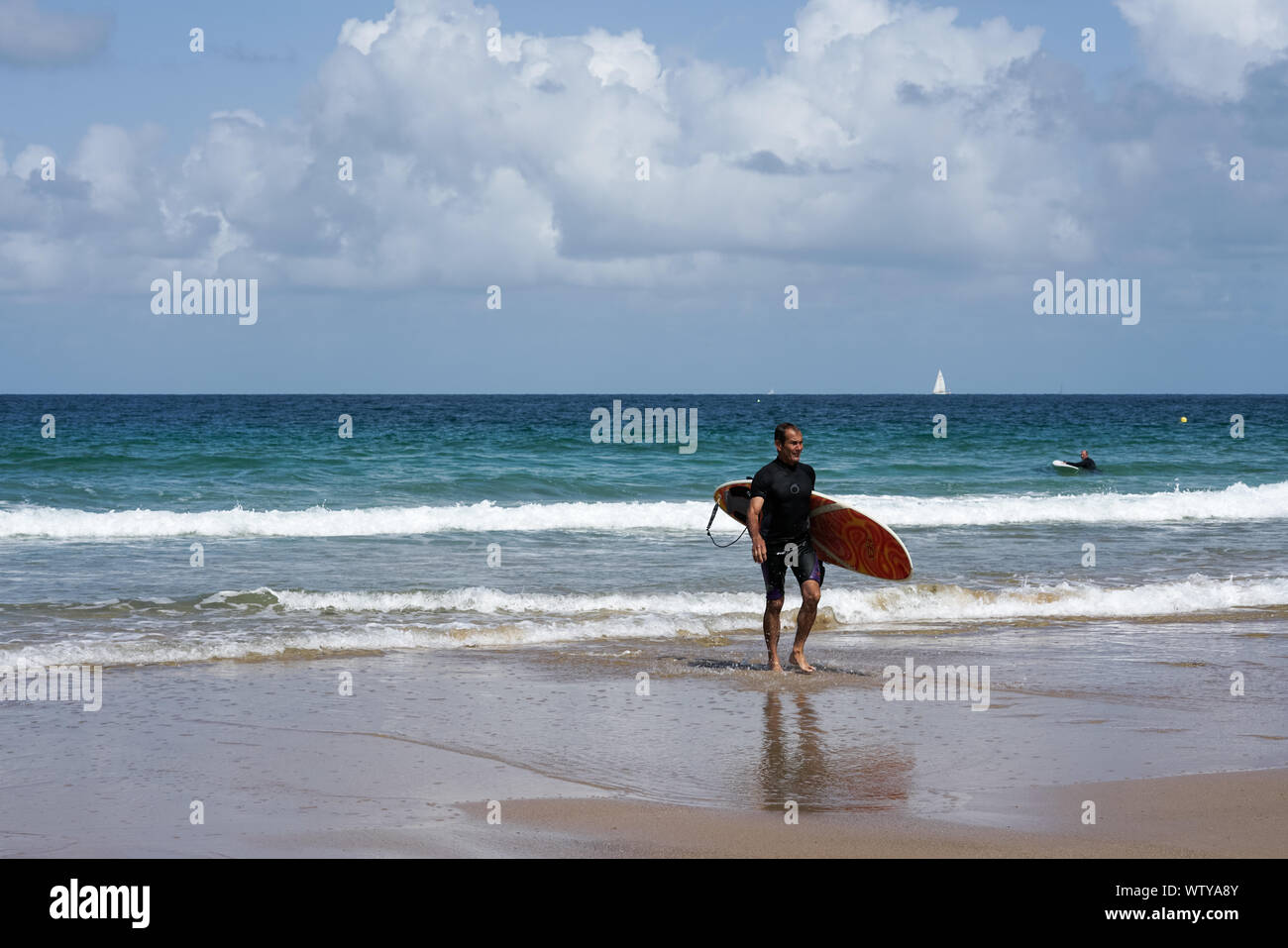 Sables D Or les Pins, Bretagne / France - 20 août 2019 : surfer la marche sur la plage après une session de surf dans les vagues sur les COA Banque D'Images