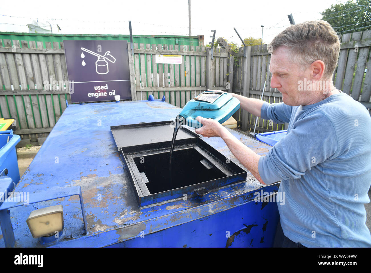 Man pouring utilisé l'huile moteur dans le bac à recyclage recyclage conseil centre uk Banque D'Images