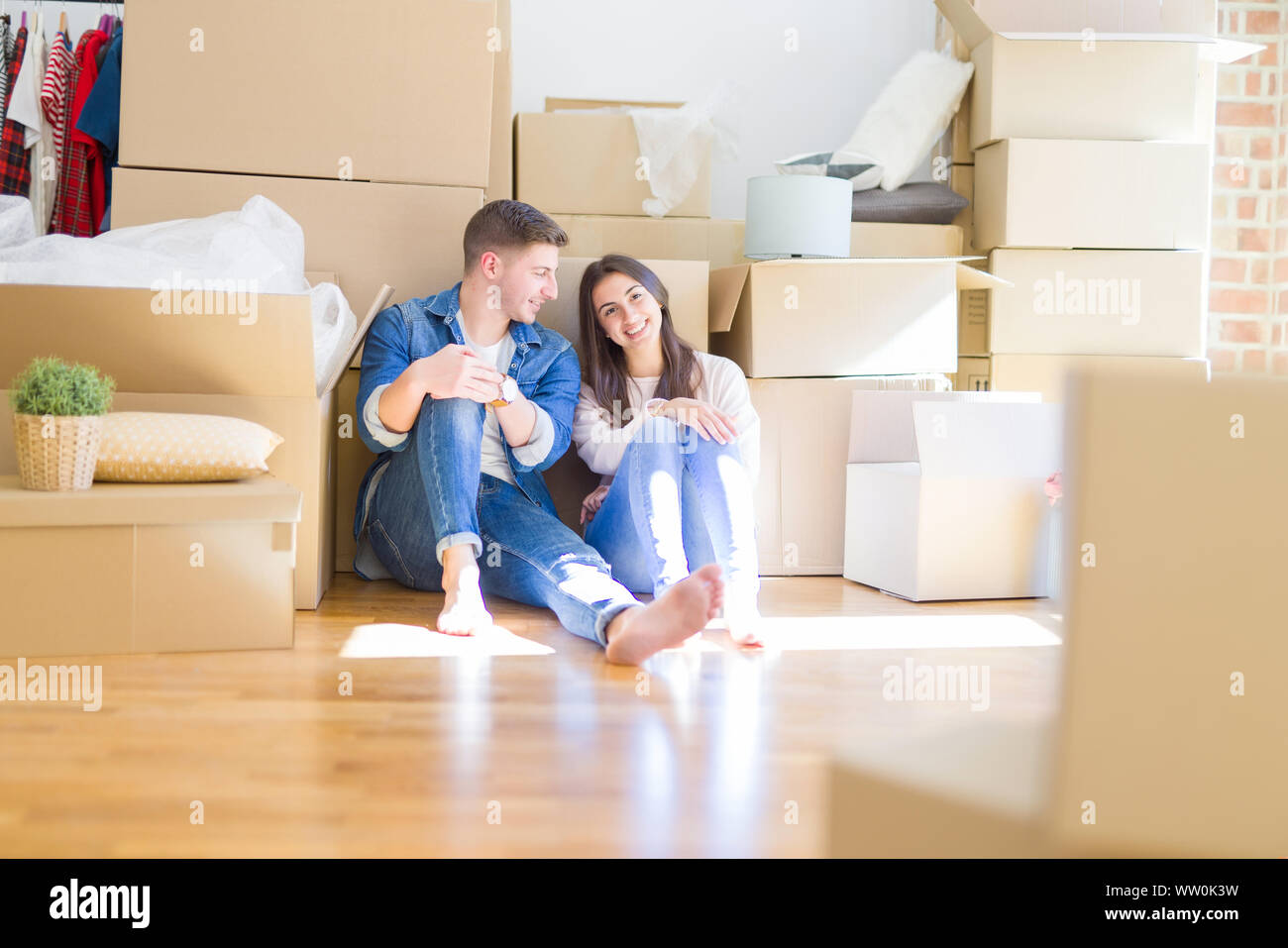 Belle jeune couple assis sur le plancher autour de boîtes de carton à la maison, souriant