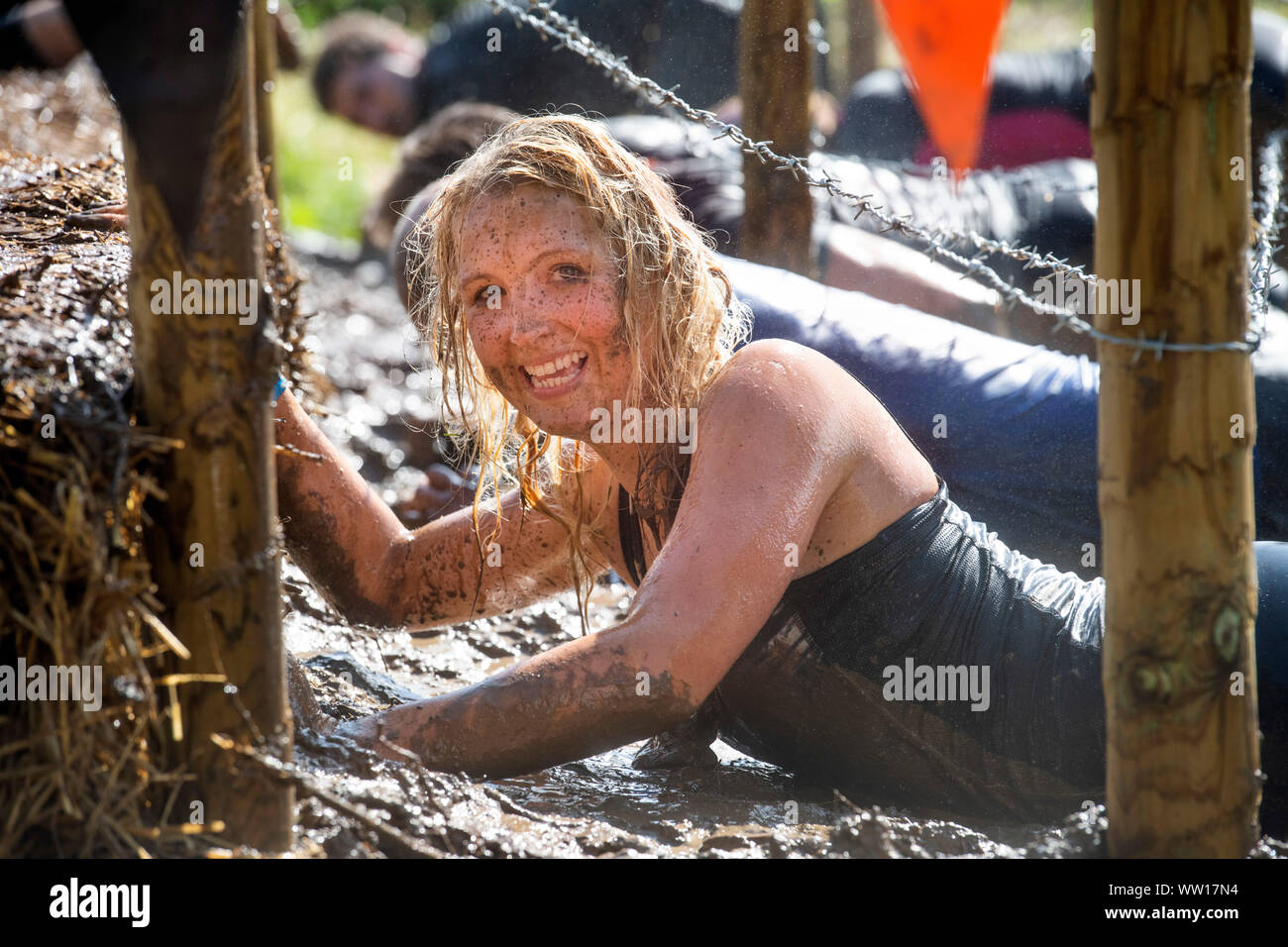 Un concurrent sur le 'Get Low' obstacle à la rude épreuve d'endurance en Badminton Mudder Park, Gloucestershire UK Banque D'Images