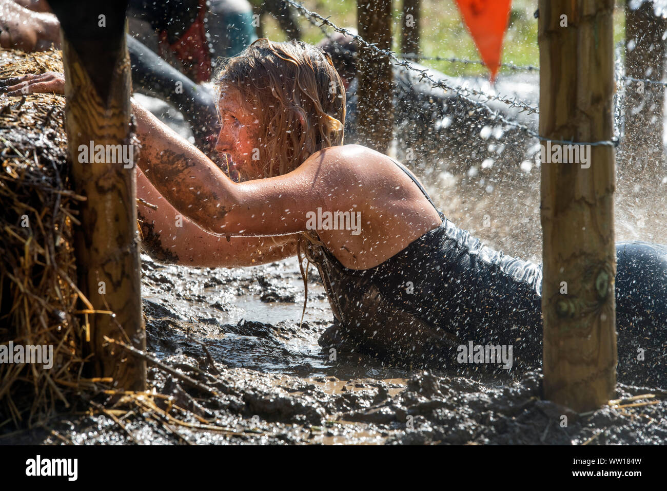 Un concurrent sur le 'Get Low' obstacle à la rude épreuve d'endurance en Badminton Mudder Park, Gloucestershire UK Banque D'Images