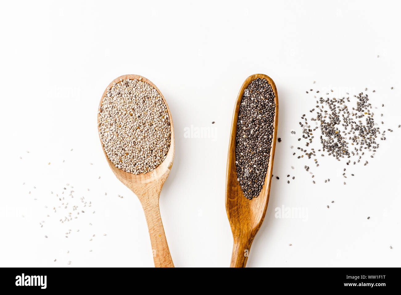 Le noir et blanc chia seeds superfood de cuillères en bois sur fond blanc Banque D'Images