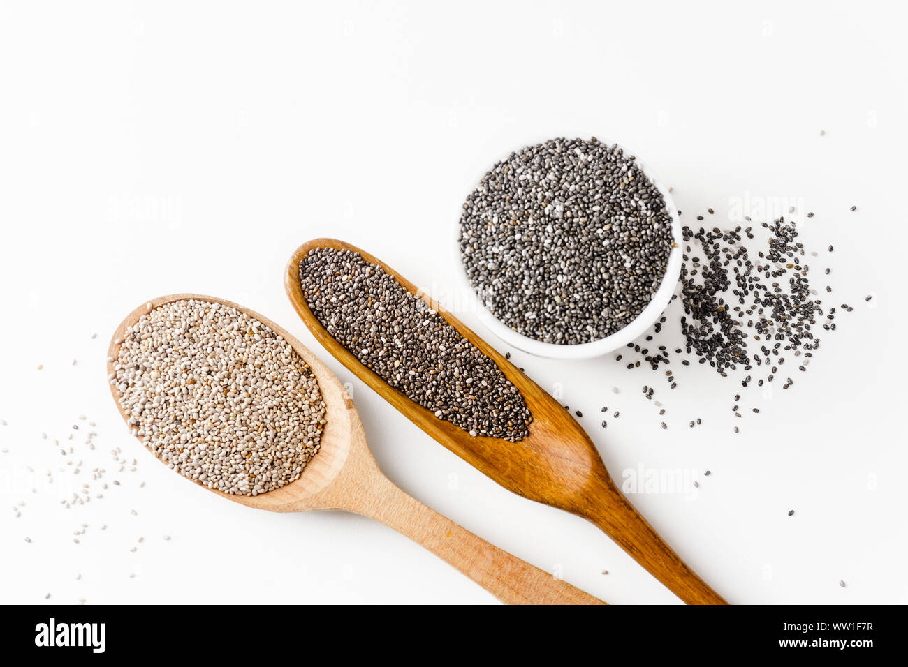 Le noir et blanc chia seeds superfood de cuillères en bois sur fond blanc Banque D'Images