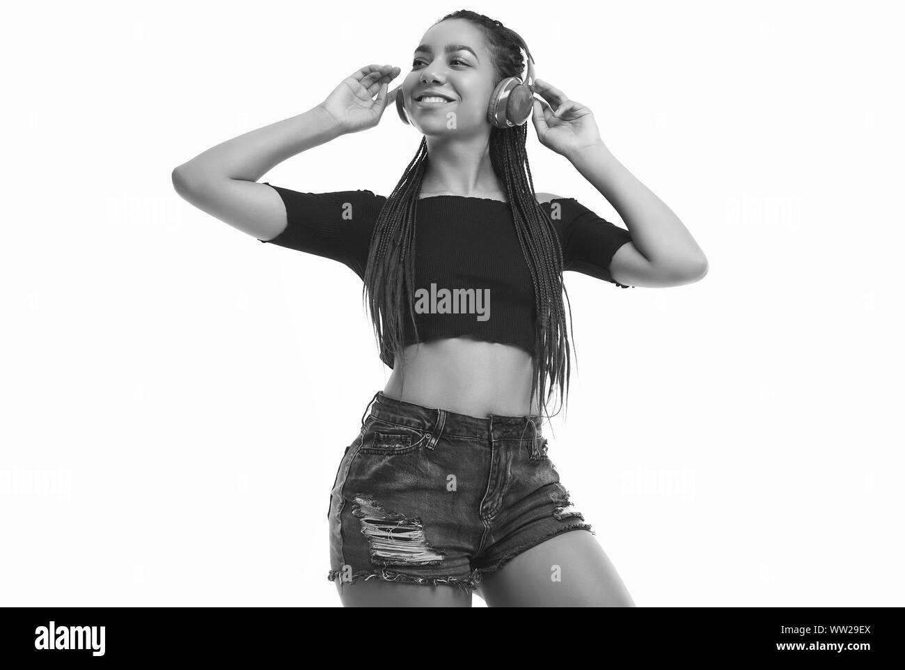 Portrait de l'Afrique belle brunette woman avec des dreadlocks à l'écoute de la musique via un casque sans fil isolé sur fond de studio Banque D'Images