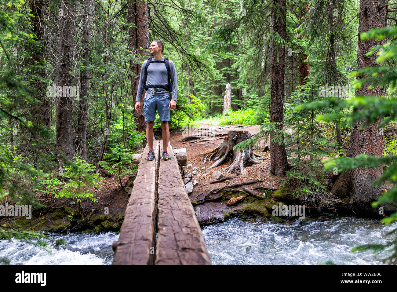 Mountain river stream avec l'homme debout dans la traversée des montagnes Rocheuses à l'été de 2019 sur le sentier du ruisseau énigme à Aspen, Colorado avec pont en bois Banque D'Images