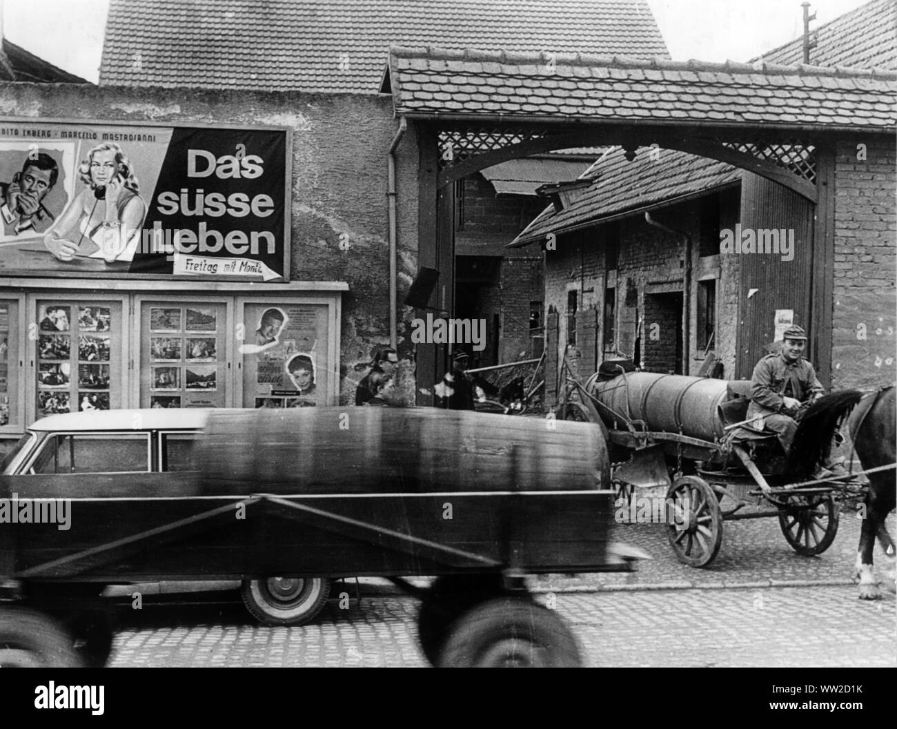 Un contraste : lisier passer une ville bavaroise sur 22.02.1961 en face d'une publicité pour le film 'Das süsse Leben' (la douce vie - La dolce vita). Dans le monde d'utilisation | Banque D'Images