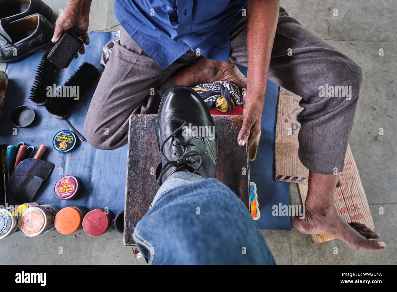 Une chaussure-polish-wallah ou cireur de l'homme au travail dans une gare ferroviaire à Mumbai, Inde Banque D'Images