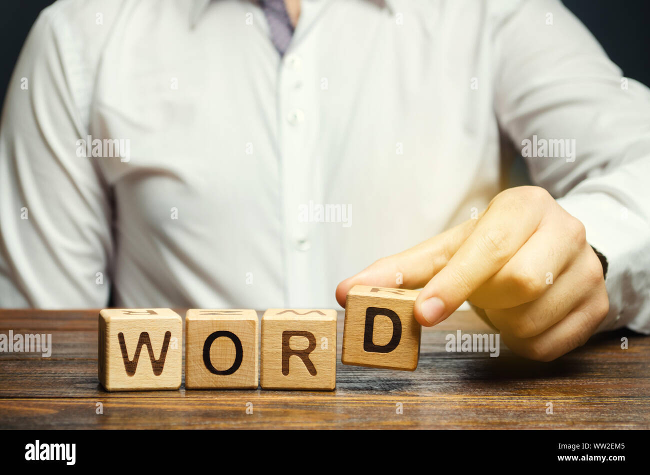 Un homme met des cales en bois avec l'inscription Mot. L'unité structurelle de la langue. La morphologie. Formation Word. Étude de la grammaire. La linguistique Banque D'Images