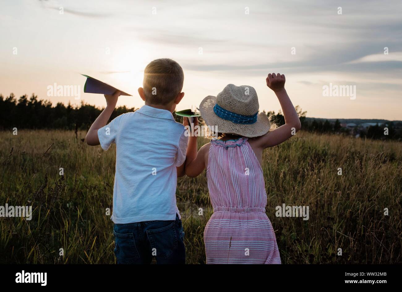 Frère et sœur à la distance en jouant au coucher du soleil Banque D'Images