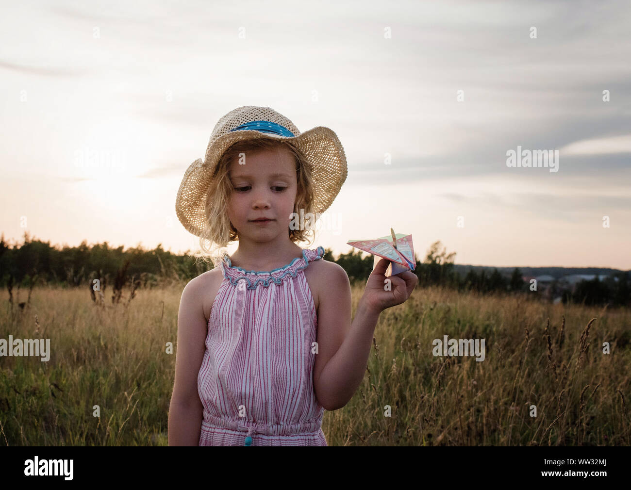 Portrait d'une jeune fille jouant dans un pré au coucher du soleil en été Banque D'Images