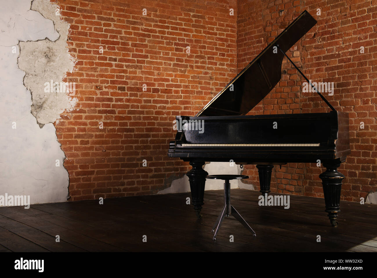 Grand piano avec couvercle surélevé et selles près de brick wall Banque D'Images