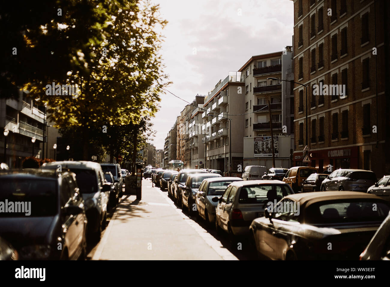 Sunny street de Paris, France, avec les voitures et ciel nuageux Banque D'Images