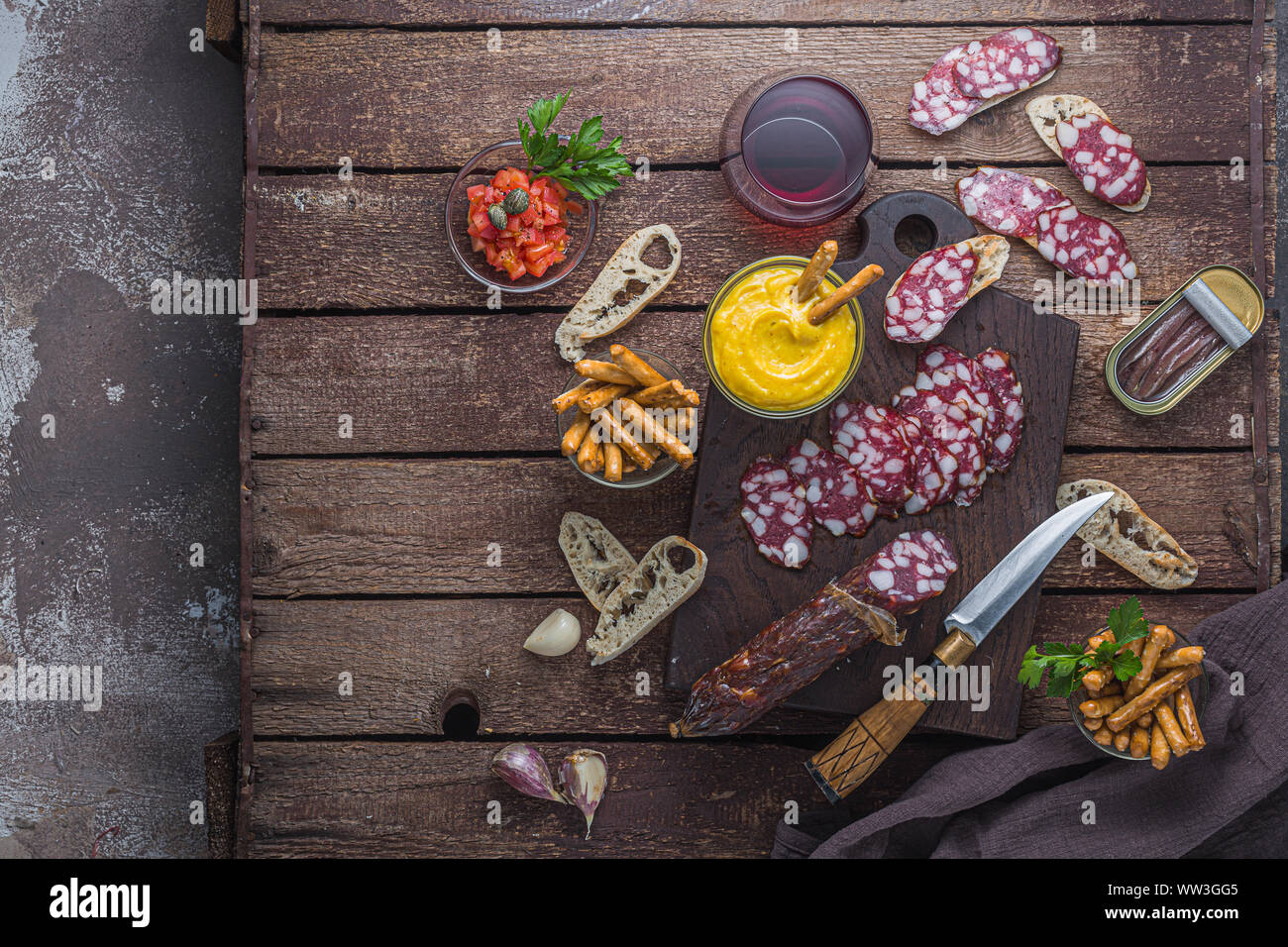 Vin rouge et planche de charcuterie : salami, du pain croustillant, anchoves, copiez l'espace. Banque D'Images