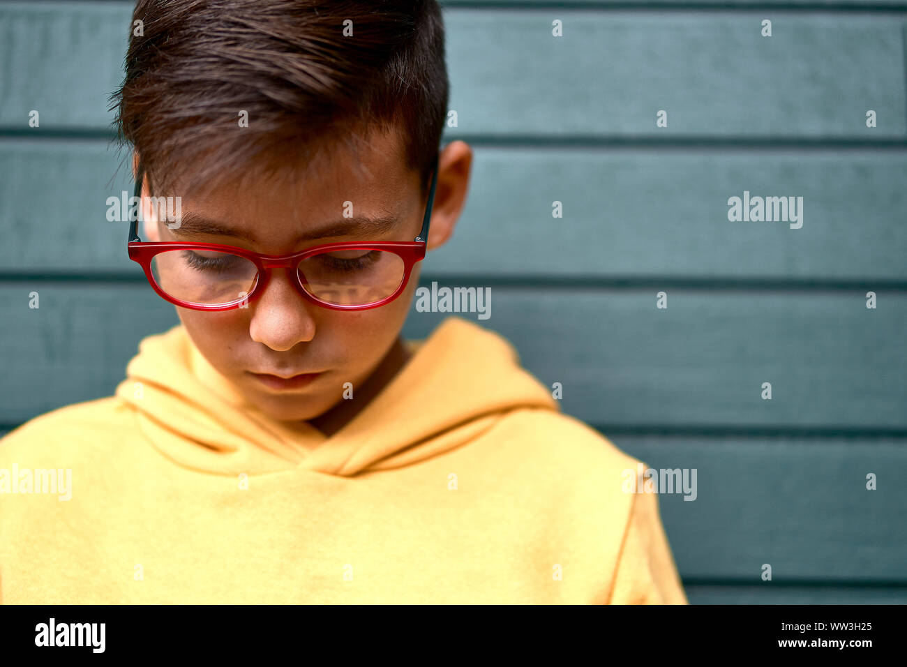 Garçon avec sweat jaune surf avec son téléphone intelligent . Fond rouge Banque D'Images