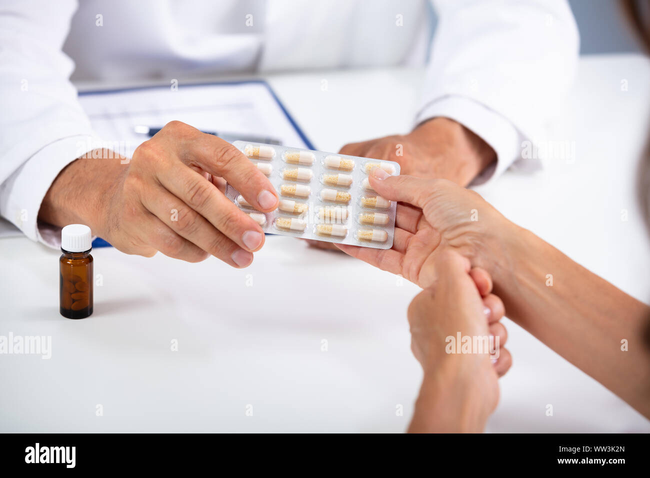 Les hommes de main du médecin donnant comprimés en plaquettes alvéolées de Female Patient In Clinic Banque D'Images