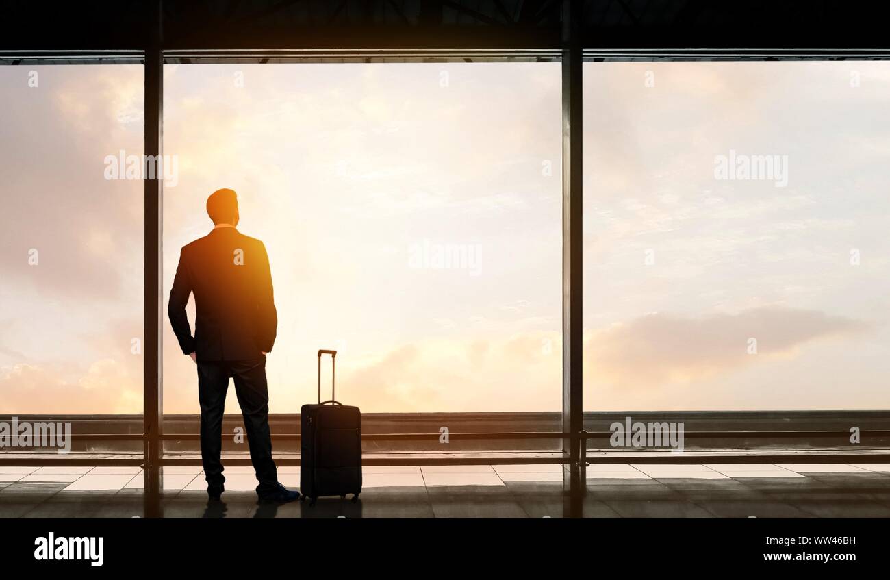 Homme debout et regardant par la fenêtre à l'aéroport en attendant le départ du vol. Banque D'Images