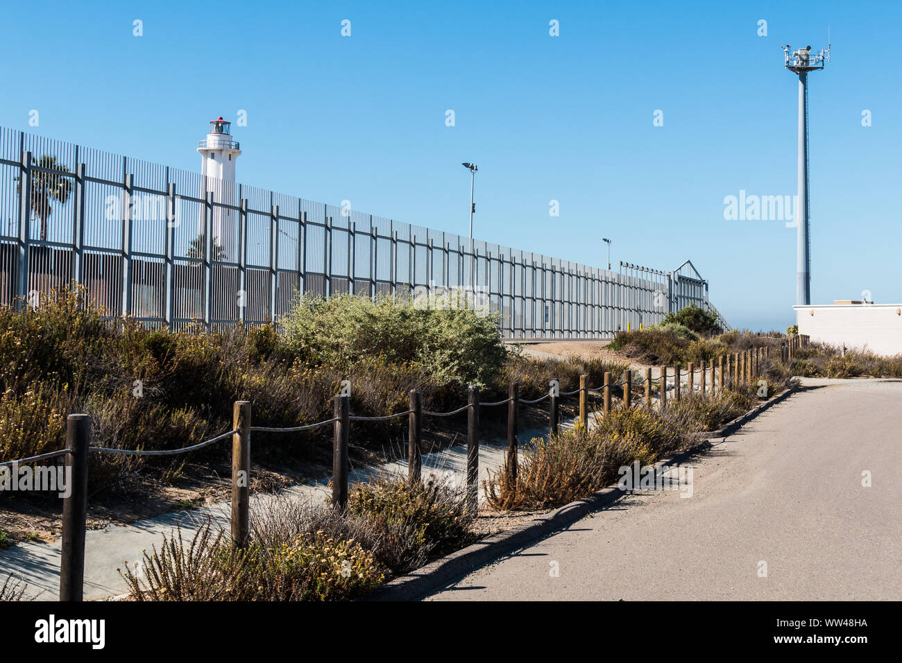 Clôture frontalière séparant San Diego, Californie et Tijuana, au Mexique, avec El Faro de Tijuana Mexique phare sur le côté et une tour de sécurité. Banque D'Images