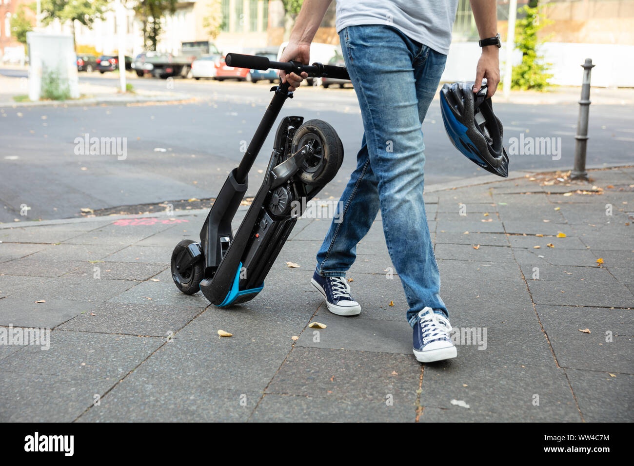 Homme portant l'E-Scooter marche sur rue pour travailler Banque D'Images