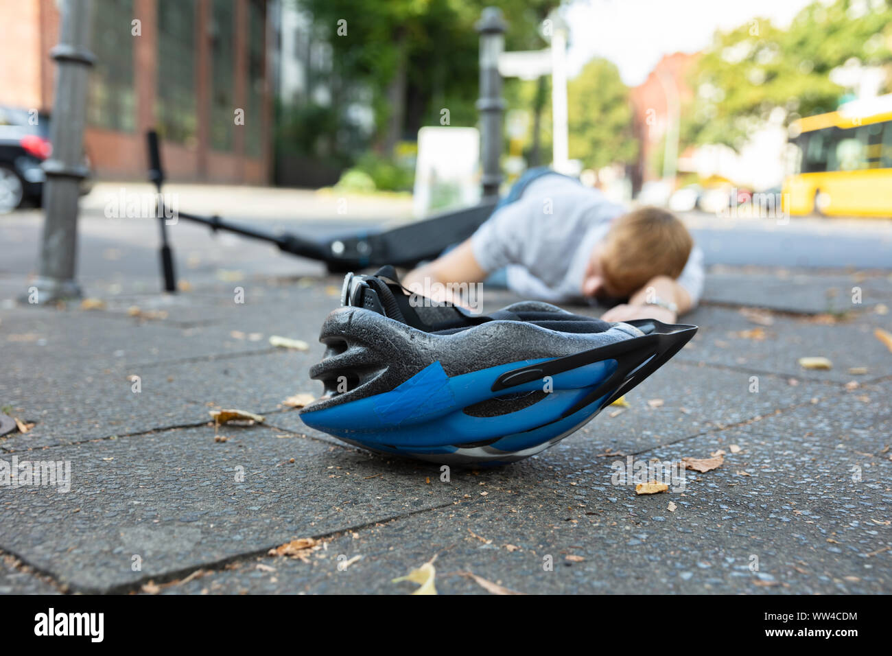 Homme inconscient allongé sur le béton rue après accident avec un Scooter électrique Banque D'Images