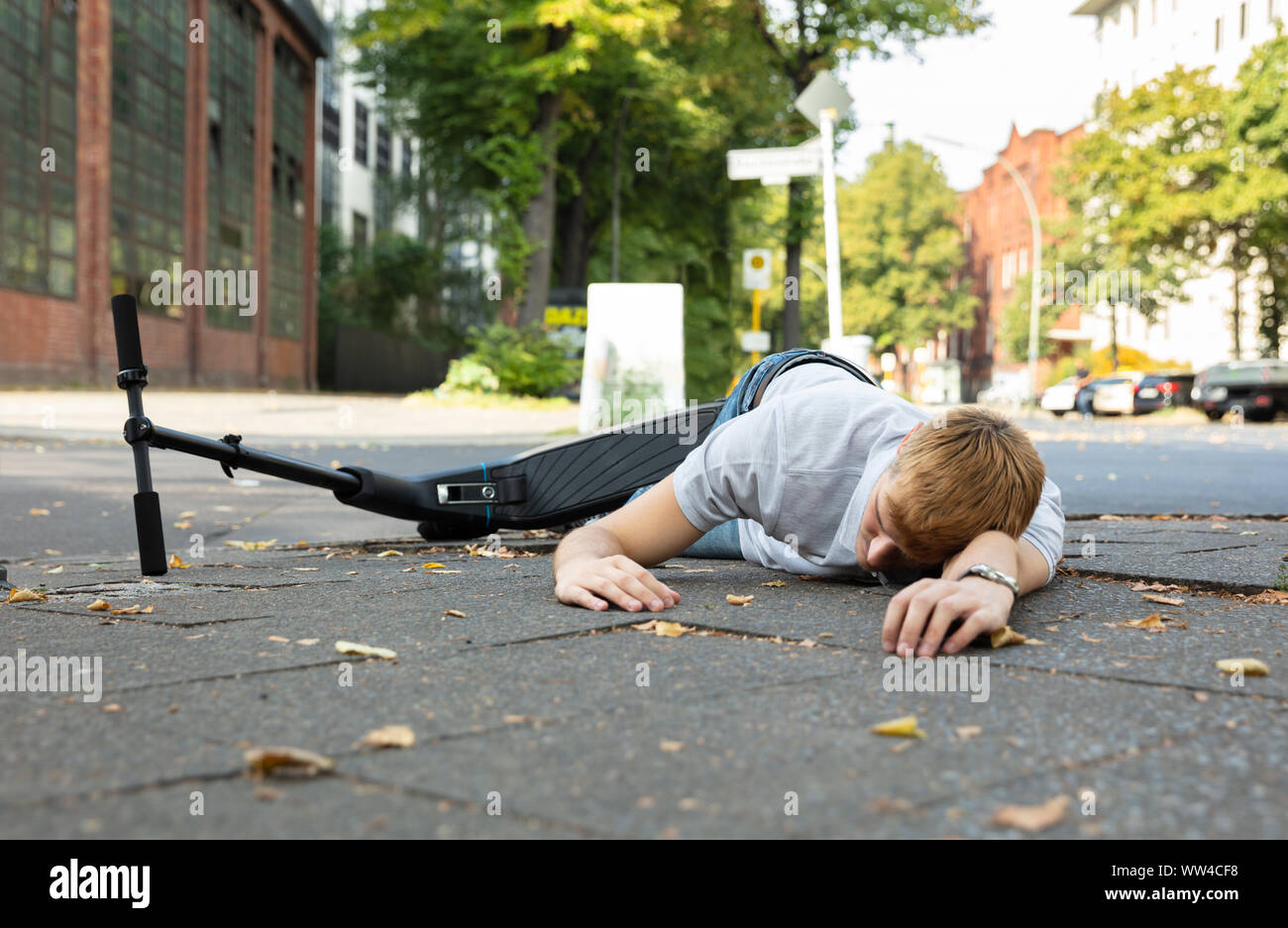 Homme inconscient allongé sur le béton rue après accident avec un Scooter électrique Banque D'Images