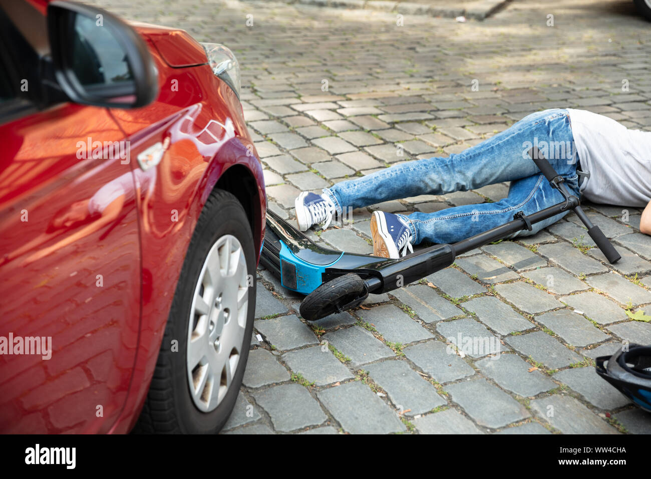 Homme après accident sur scooter électrique envahie par voiture Banque D'Images