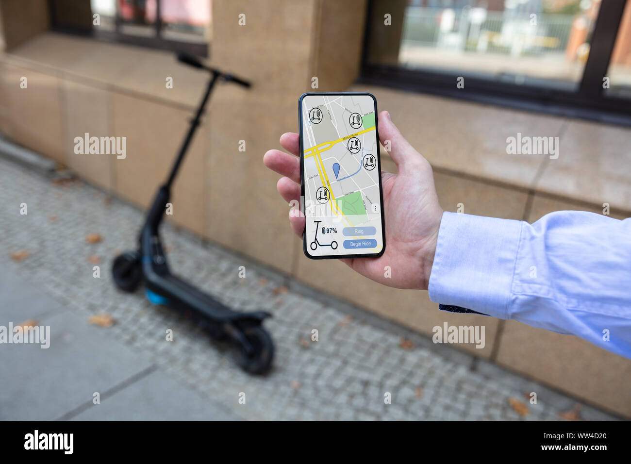 Jeune homme à l'aide de l'App à louer Scooter électrique Banque D'Images