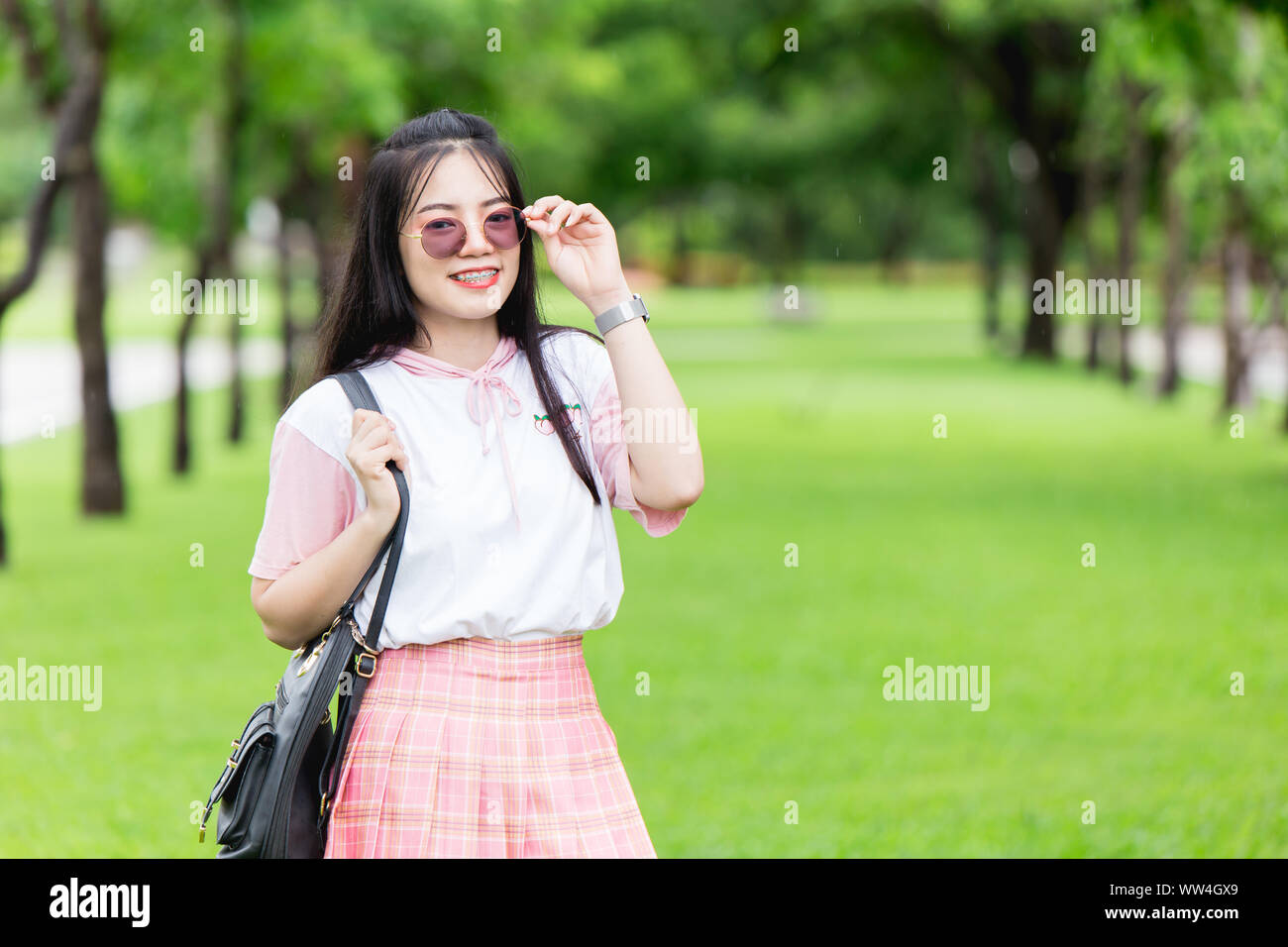Asian girl teen mignon avec renfort lunettes UV de dents fond green park Banque D'Images