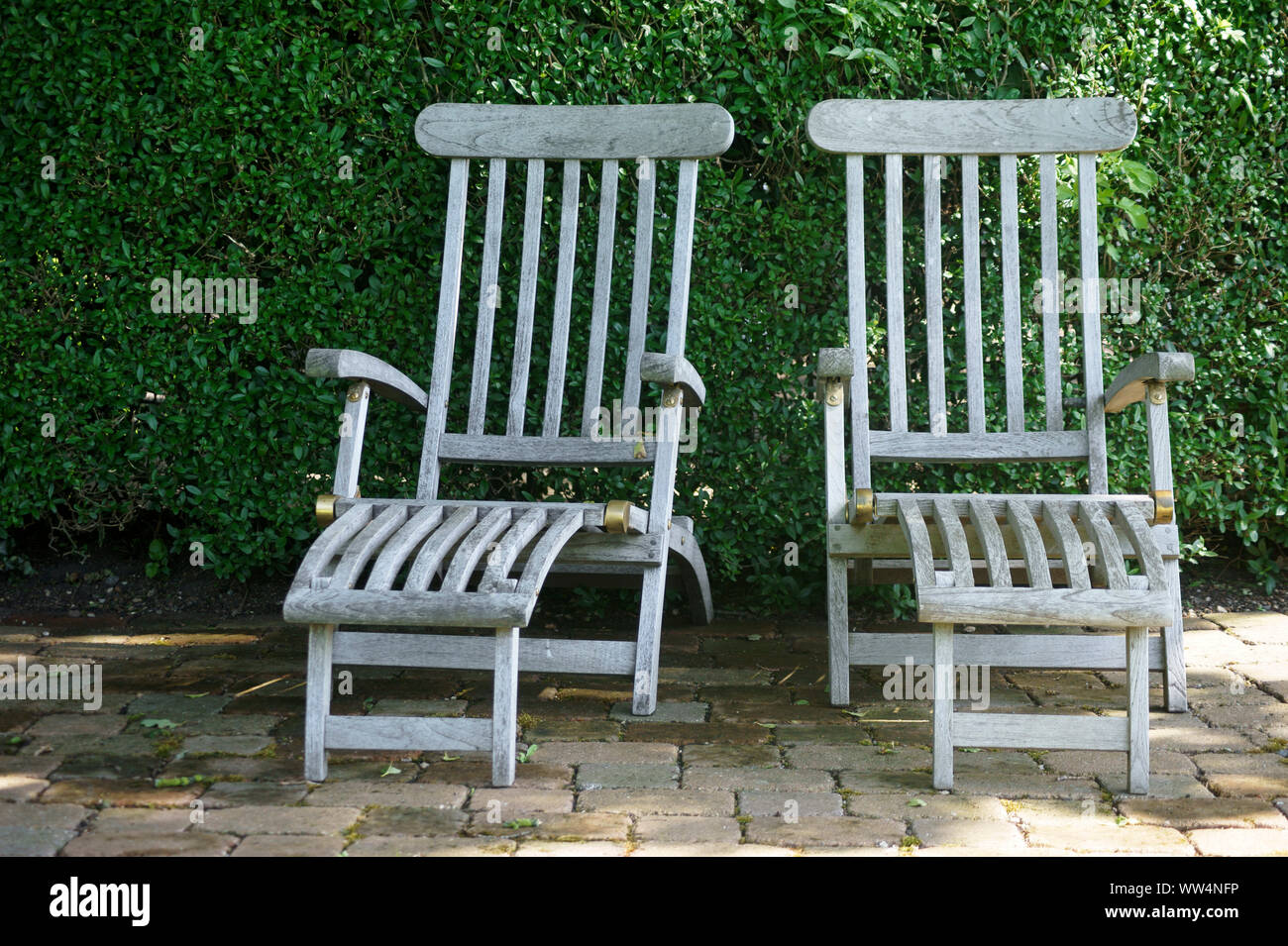 Deux chaises de jardin en teck en face d'une couverture verte à la lumière du soleil, Banque D'Images