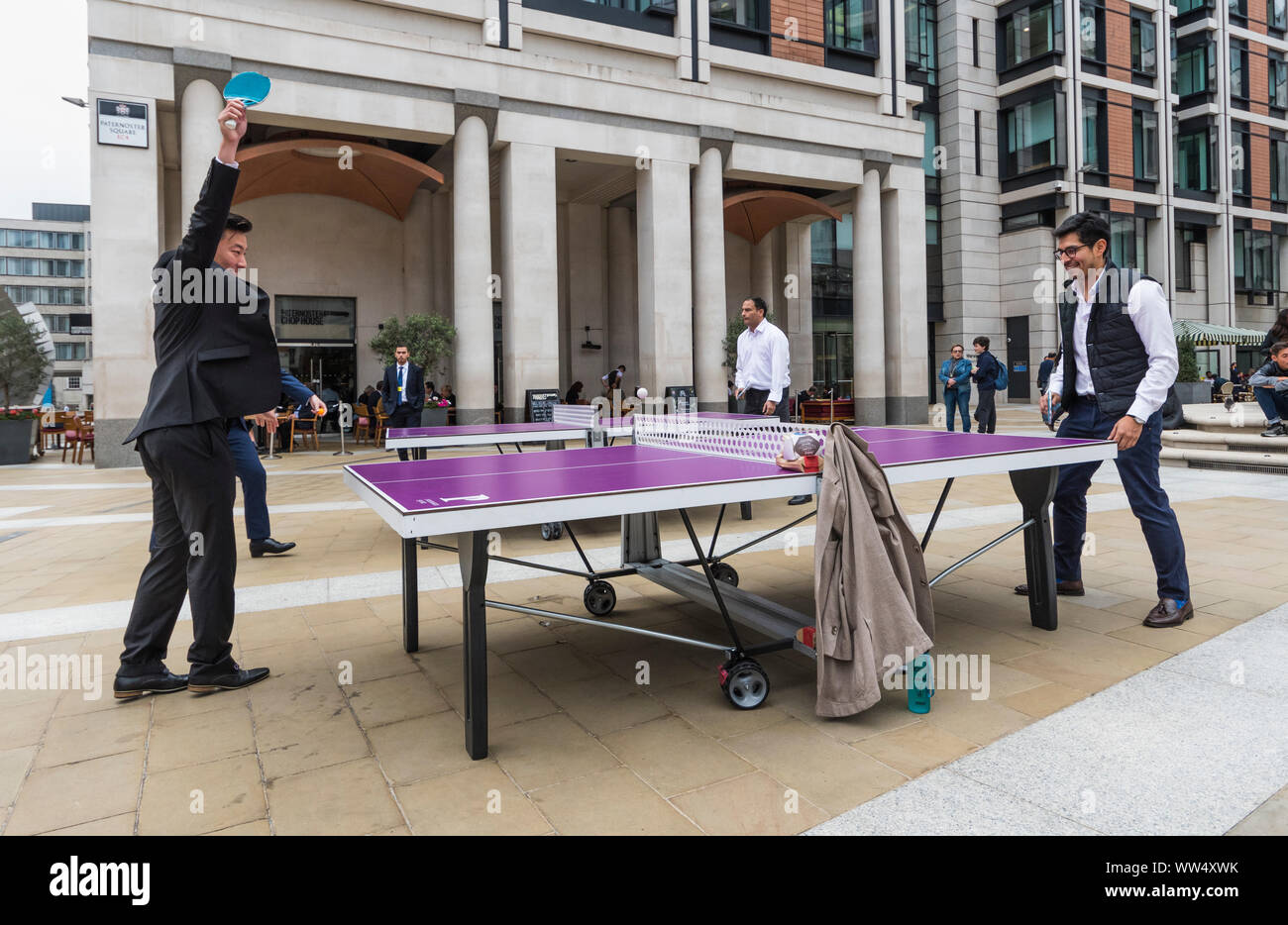 Les hommes d'affaires à jouer au tennis de table (Ping Pong) à l'extérieur à Paternoster Square, City of London, England, UK. Table de tennis de table. Banque D'Images