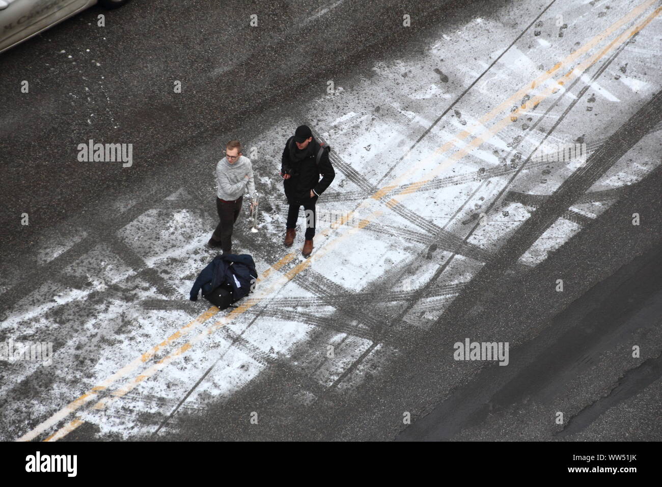 Deux jeunes hommes se tenant debout sur un snow-covered center strip d'une rue, Banque D'Images