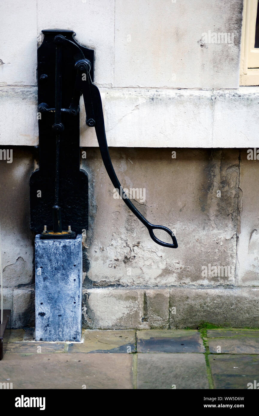 Un vieux nostalgique de la pompe hydraulique à un mur d'une maison, Banque D'Images