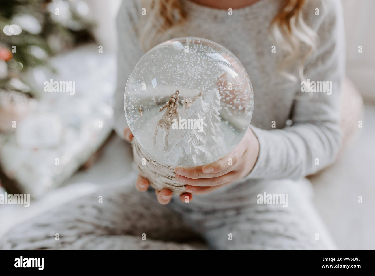 Fille assise sur le sol tenant un globe de neige à Noël Banque D'Images