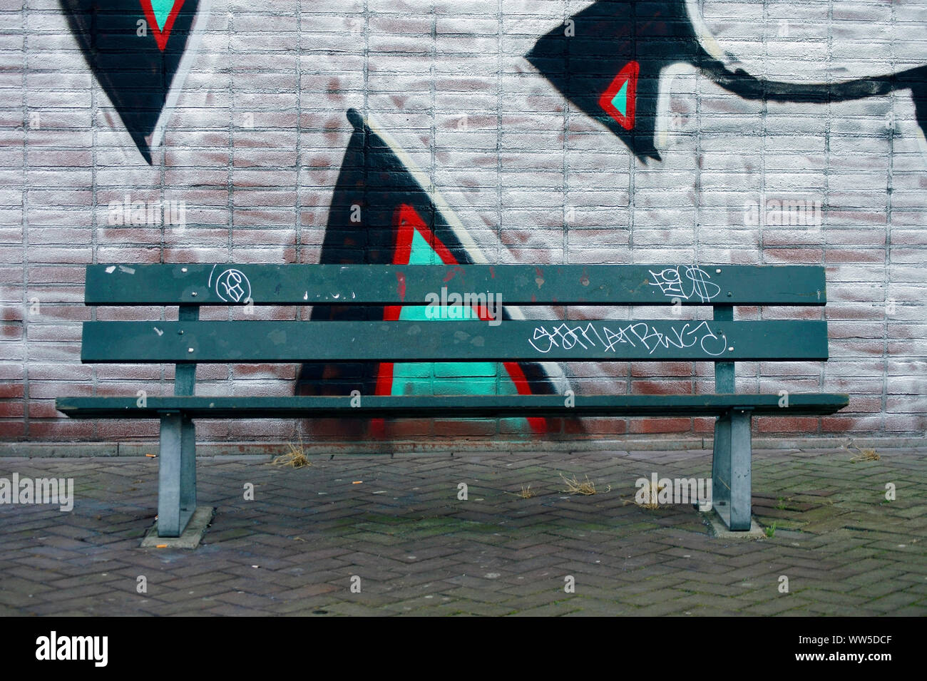 Un banc de parc, debout devant un bâtiment avec les graffitis, Banque D'Images