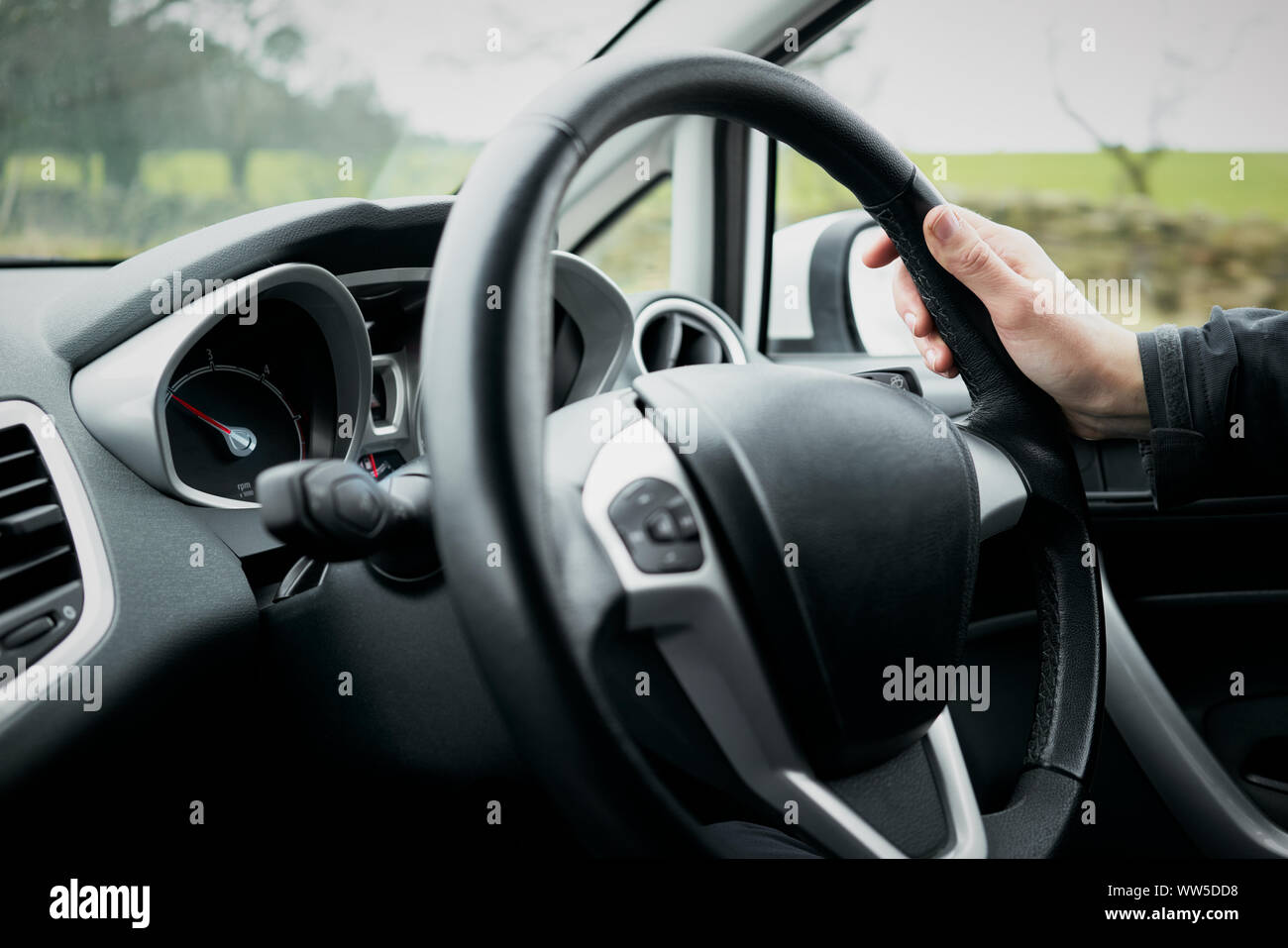 Une main de femme tenant un volant d'une voiture pendant la conduite. Banque D'Images