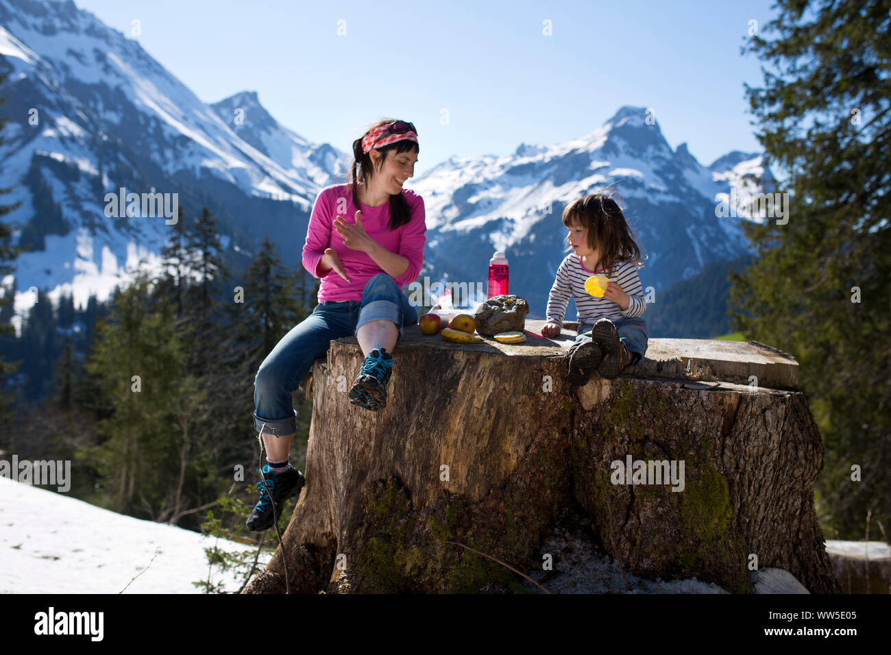 Mère avec enfant pique-nique sur un tronc, paysage de montagne dans l'arrière-plan Banque D'Images