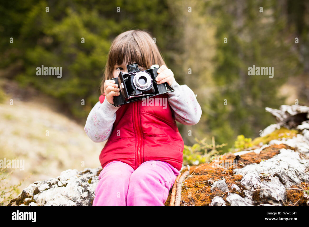3-6 ans Girl in red waistcoat prendre des photos avec un ancien appareil photo Banque D'Images