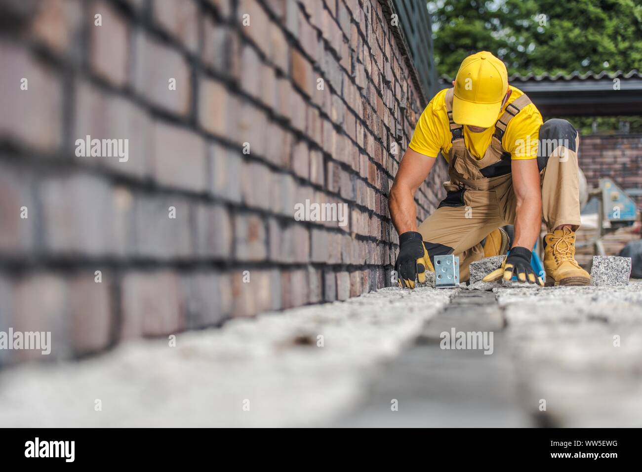 Pavage en brique granit travailleur. Entrepreneur résidentiel construction allée. Banque D'Images