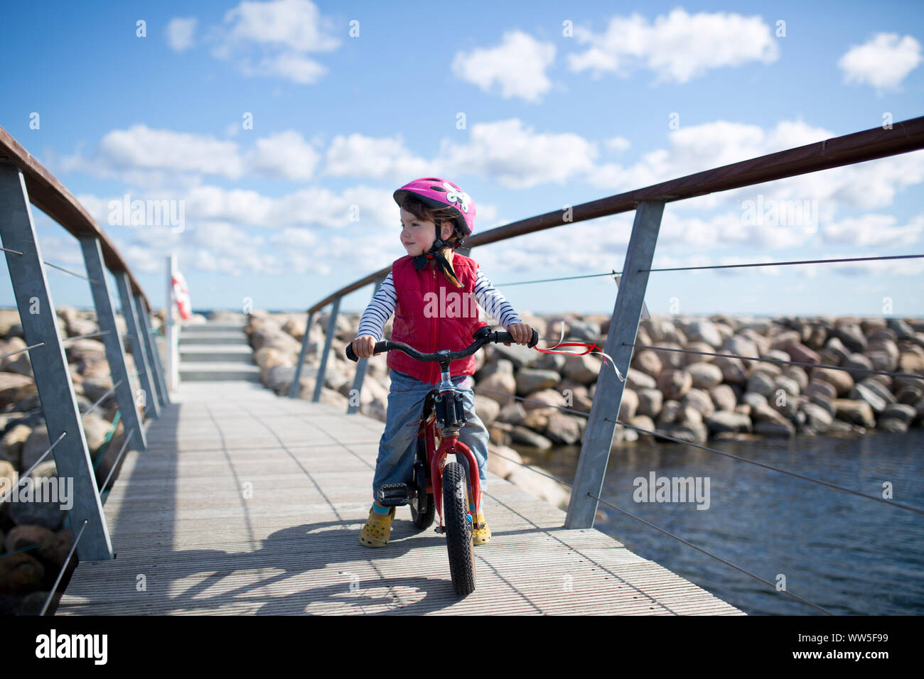 4-6 ans fille équitation pour enfants rouge location sur le pont à la côte de la mer Baltique Banque D'Images