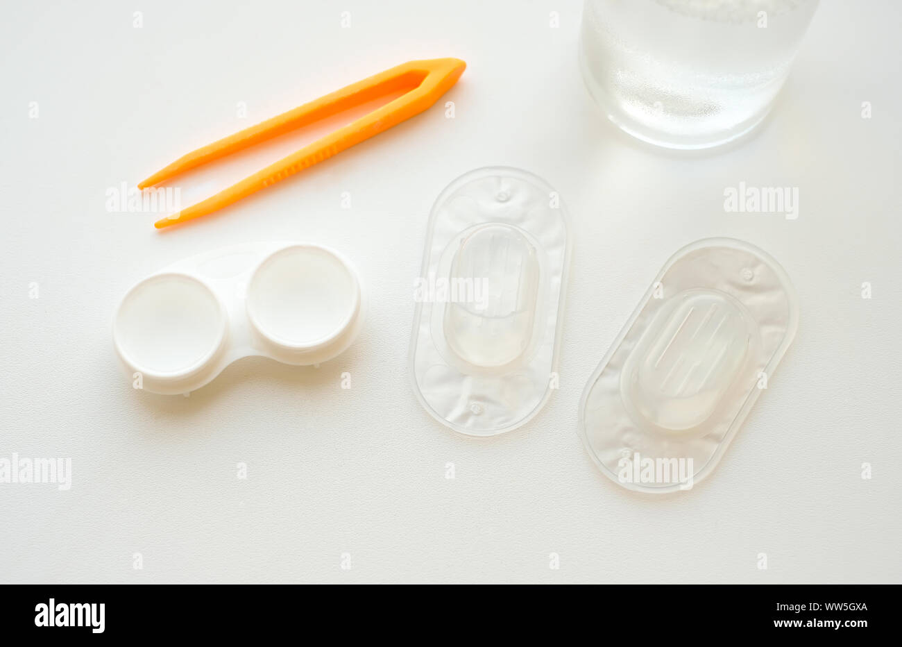 Accessoires pour l'utilisation des lentilles de contact : boîtier, brucelles, blister et solution sur fond blanc. Correction de la vision en toute sécurité. Vue de dessus. Banque D'Images