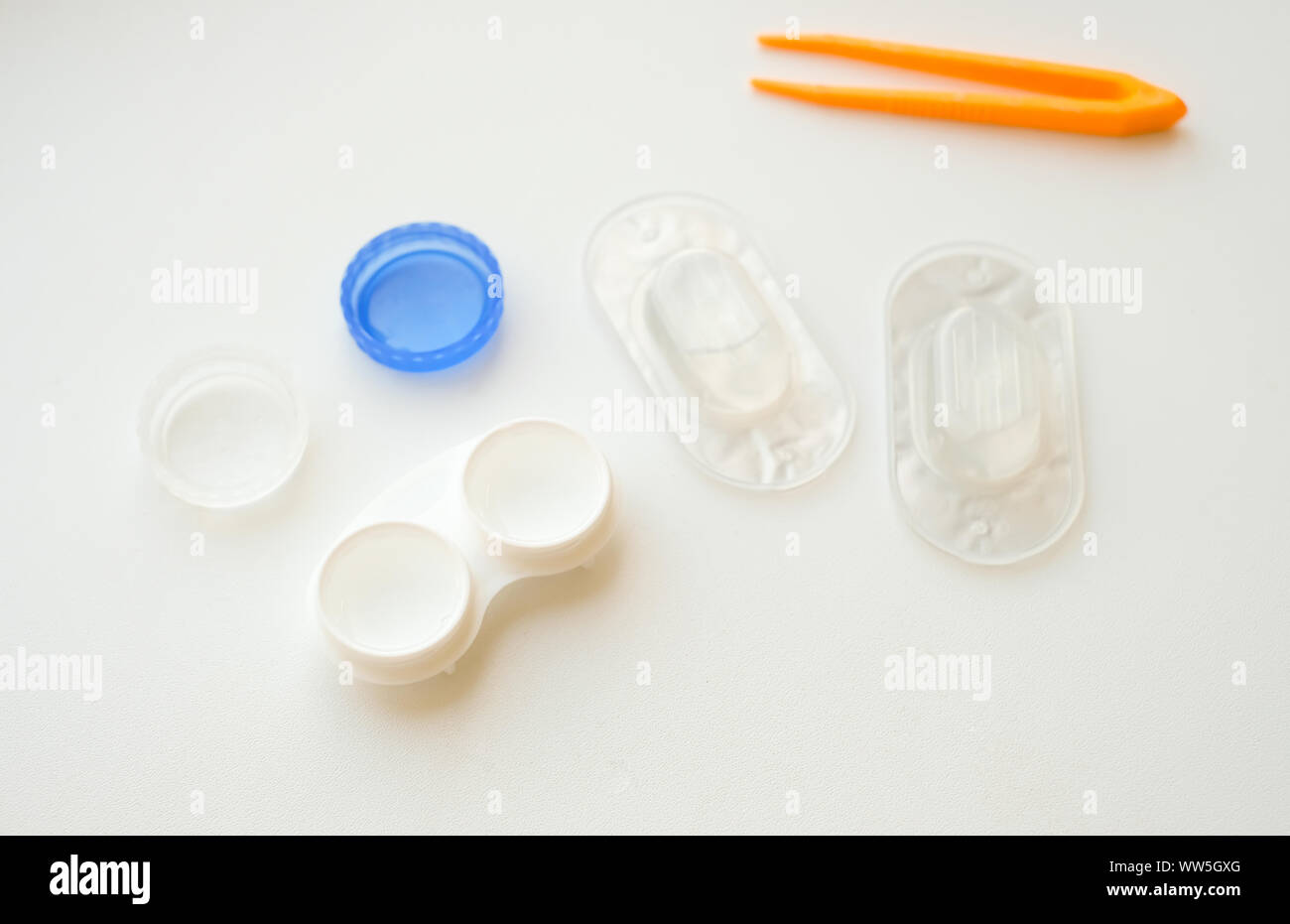 Accessoires pour l'utilisation des lentilles de contact : boîtier, brucelles, blister et solution sur fond blanc. Correction de la vision en toute sécurité. Vue de dessus. Banque D'Images